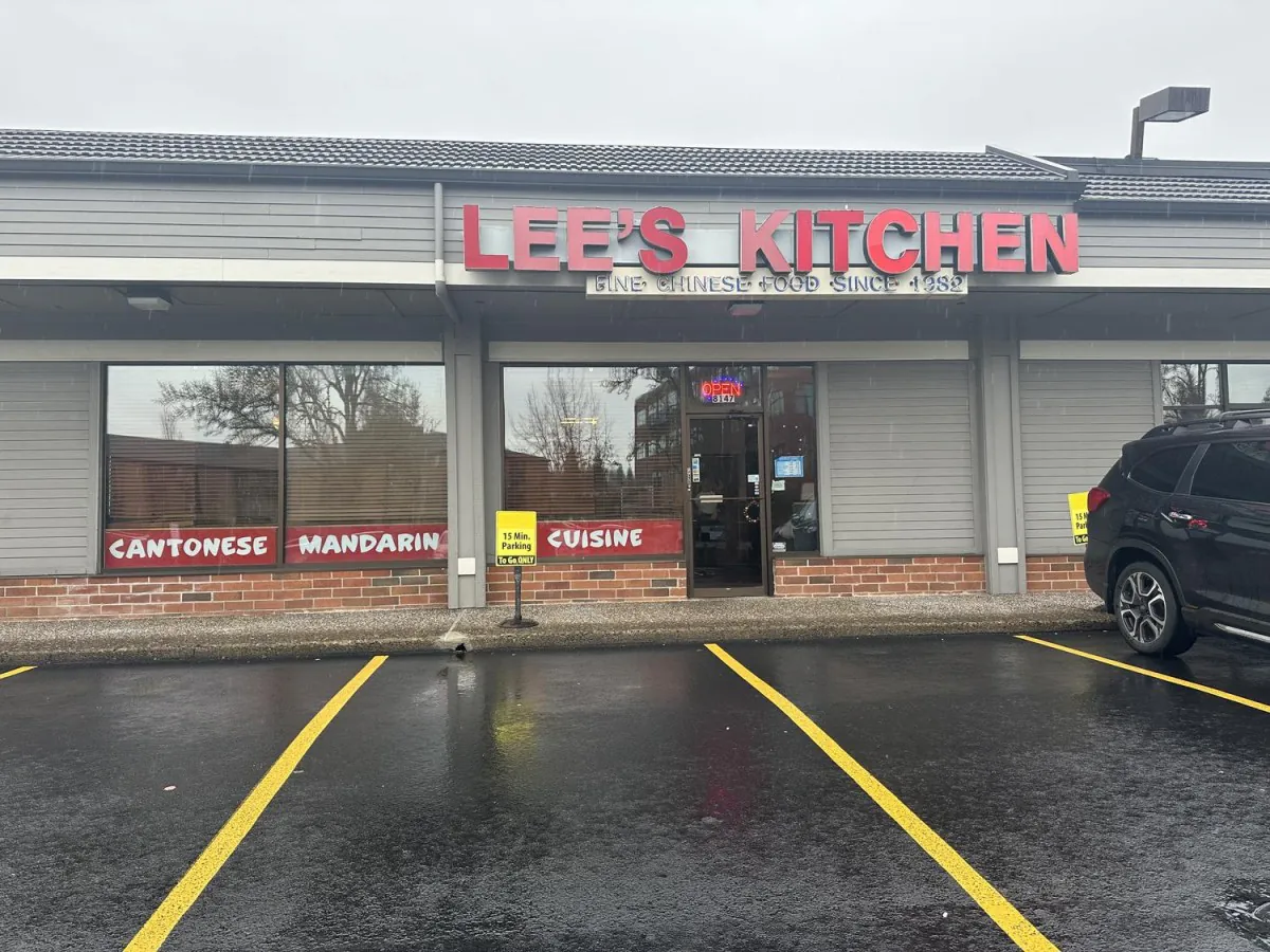 Exterior of Lee's Kitchen, a Chinese restaurant with red signage and a wet parking lot.
